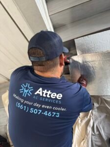 HVAC technician cutting ductwork with Attee AC Services logo visible