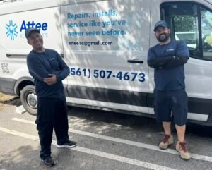 Two Attee AC Services technicians posing beside a branded service van