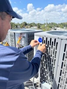 HVAC technician placing identification stickers on a rooftop AC unit